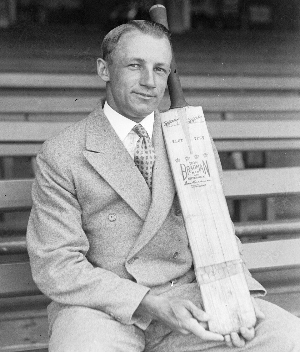 Sir Donald Bradman in 1932, seated, holding a cricket bat.